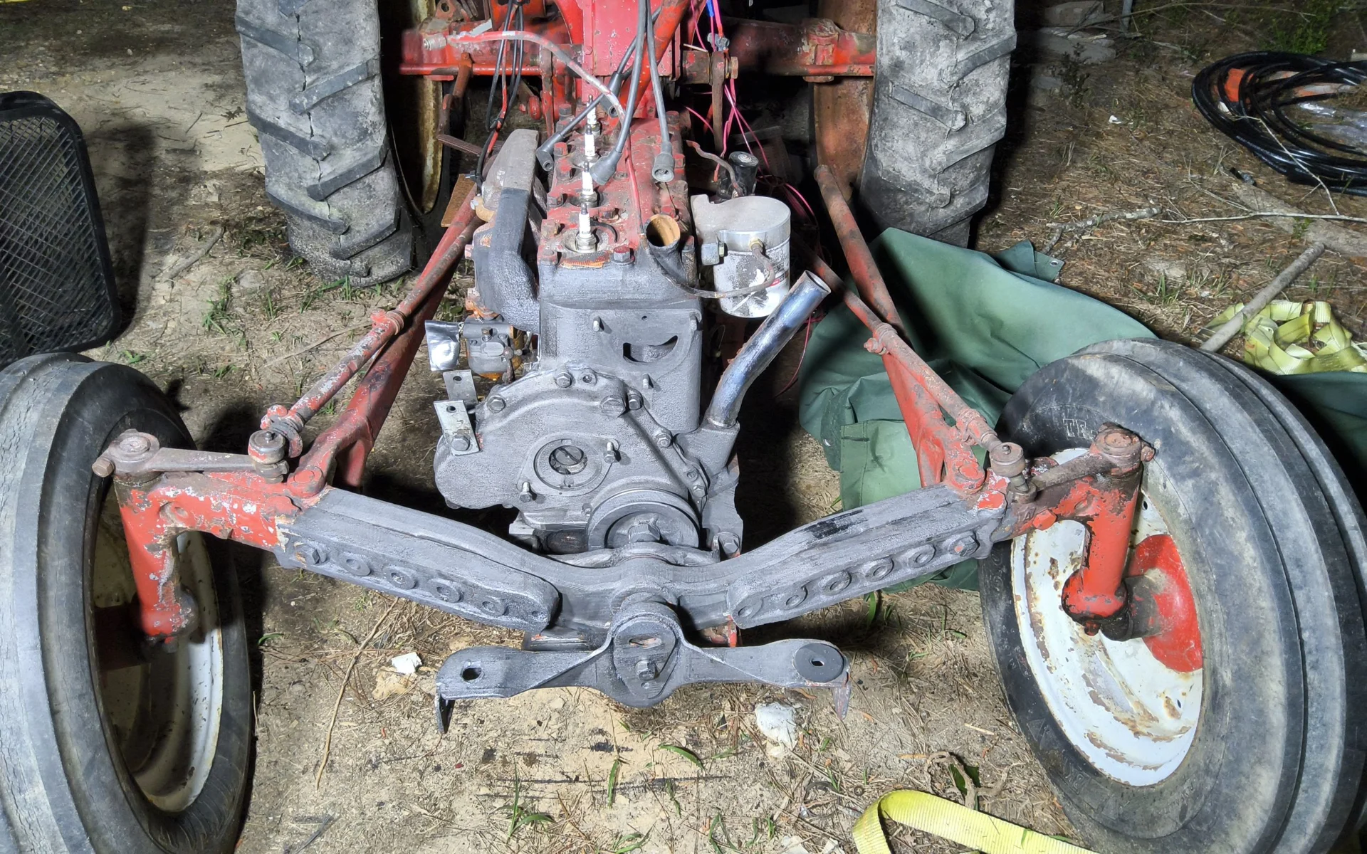 Tractor engine and chassis with cleaned metal sections beside remaining red paint
